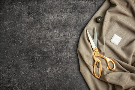 Scissors, fabric, chalk and pins with needles on dark backgroundの写真素材