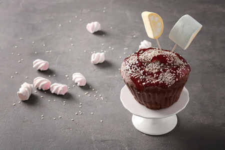 Dessert stand with delicious cupcake on grey background