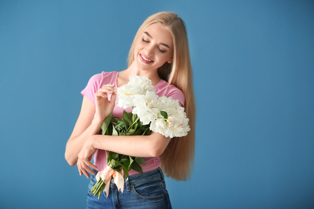 Attractive young woman with beautiful flowers on color backgroundの写真素材