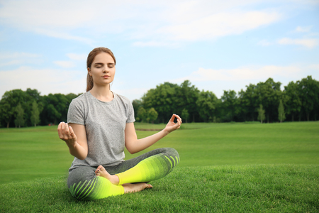 Young woman practicing yoga in parkの写真素材