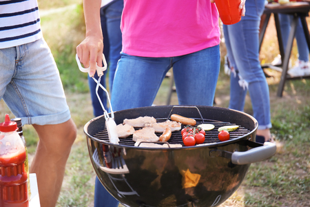 People preparing meat and vegetables on modern grill outdoorsの写真素材
