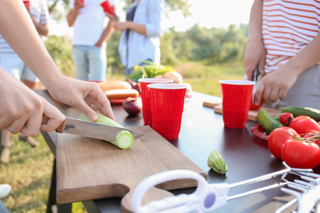 Young people cutting vegetables for barbecue party outdoorsの写真素材