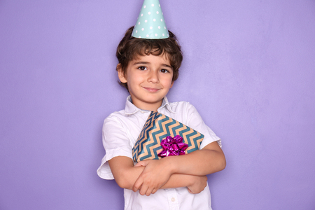 Cute little boy with gift for his birthday on color backgroundの写真素材