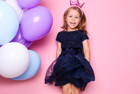Cute little girl with balloons on color background. Birthday celebrationの写真素材