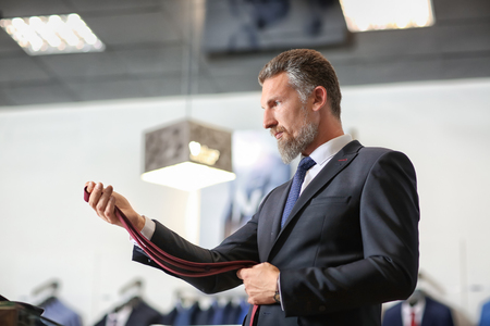 Handsome mature man choosing accessories in menswear storeの写真素材