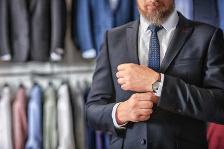 Mature businessman in suit with wristwatch in menswear storeの写真素材