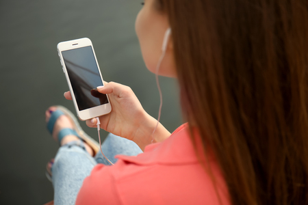 Young woman listening to music near riverの写真素材