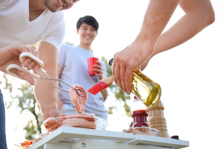 Young people preparing meat for barbecue party outdoorsの写真素材