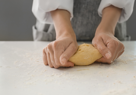 Woman kneading dough for bakery on kitchen tableの写真素材