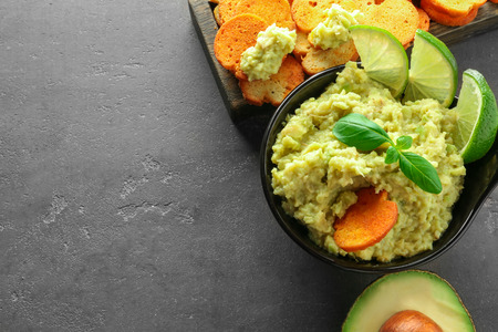 Bowl with tasty guacamole and bread chips on grey textured backgroundの写真素材