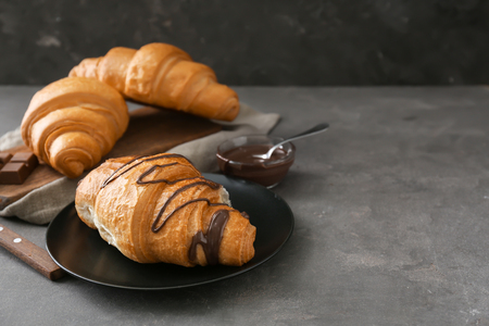 Plate with tasty croissant and chocolate sauce on grey tableの写真素材