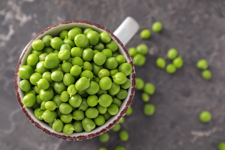 Cup with delicious fresh green peas on grey textured backgroundの写真素材