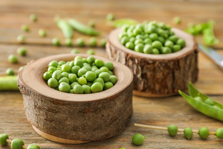 Bowls with delicious fresh green peas on wooden tableの写真素材