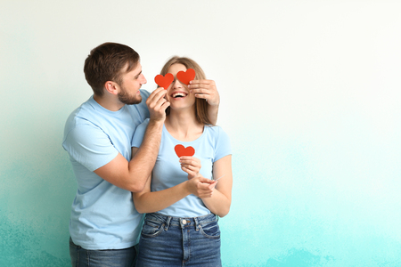 Happy young couple with red hearts on color backgroundの写真素材