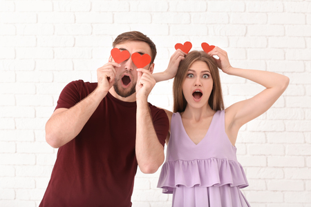 Happy young couple with red hearts on light backgroundの写真素材