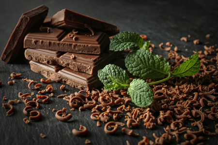 Tasty milk chocolate pieces and shavings on dark tableの写真素材