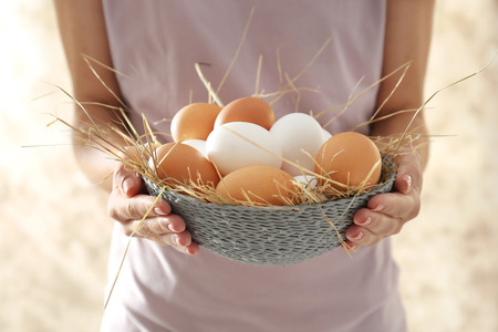 Woman holding wicker bowl with chicken eggs, closeupの写真素材