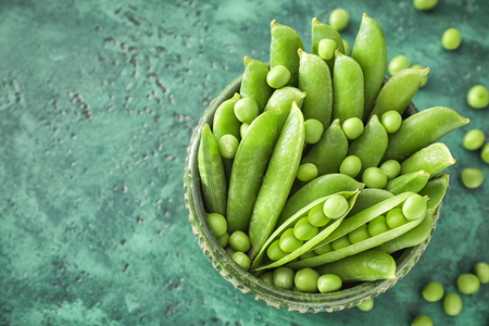 Bowl with green peas on color backgroundの写真素材