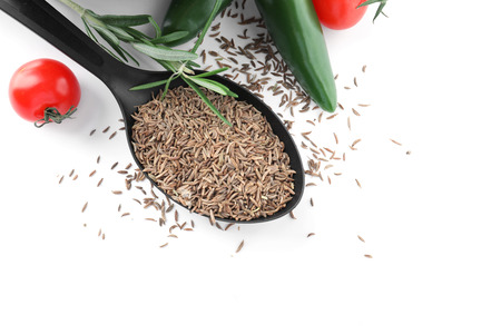 Spoon with cumin seeds, rosemary and vegetables on white background