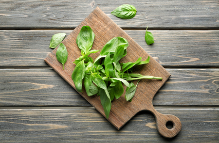 Wooden board with fresh basil on tableの写真素材