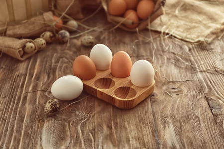 Wooden holder with chicken eggs on tableの写真素材
