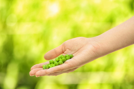 Young woman holding fresh green peas outdoors, closeupの写真素材