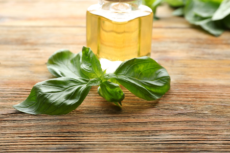 Jar of oil with fresh basil on wooden tableの写真素材