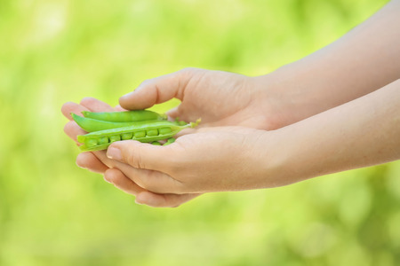 Young woman holding fresh green peas outdoors, closeupの写真素材