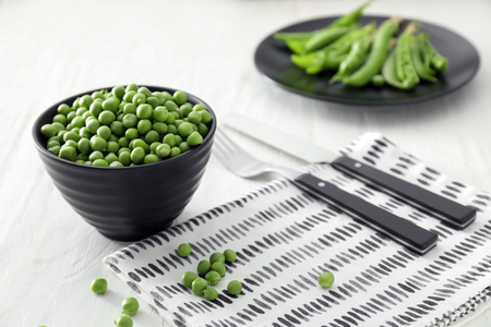 Bowl with delicious fresh green peas on white wooden tableの写真素材
