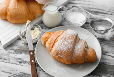 Plate with tasty croissants, butter and milk on wooden backgroundの写真素材