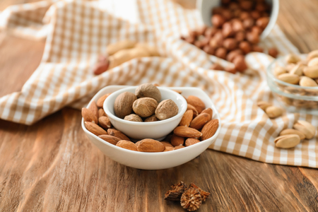 Bowls with different nuts on wooden tableの写真素材