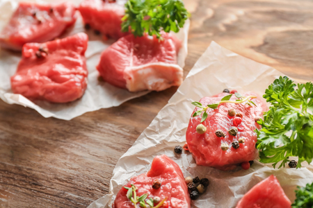 Fresh raw meat with spices and herbs on wooden tableの写真素材