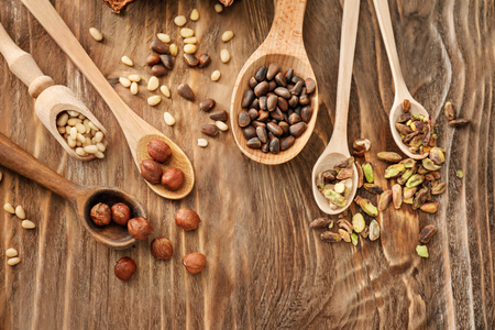 Spoons with different nuts on wooden backgroundの写真素材