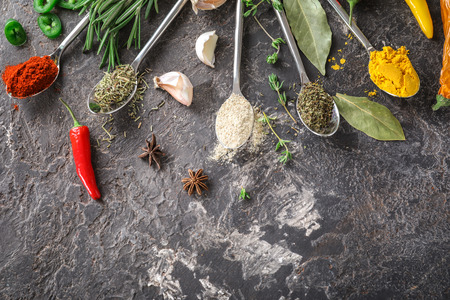 Different kinds of spices with herbs on grey backgroundの写真素材