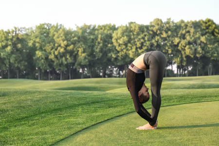 Beautiful young woman practicing yoga outdoors in the morningの写真素材