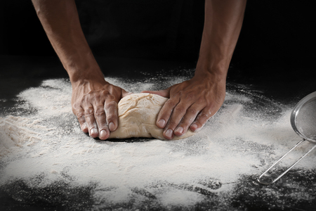 Man kneading dough on black backgroundの写真素材