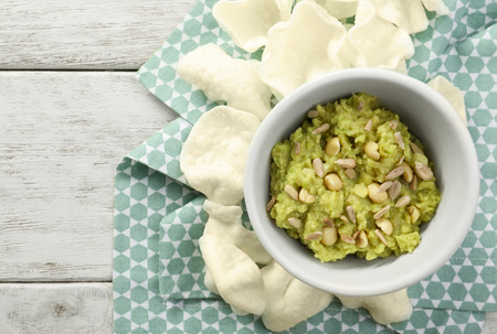 Bowl with tasty guacamole and crunchy snacks on wooden tableの写真素材