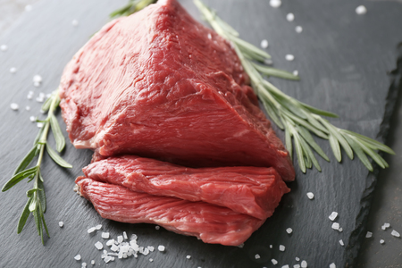 Fresh raw meat with rosemary on slate plateの写真素材