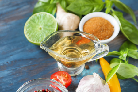 Gravy boat with oil with herbs and spices on wooden table