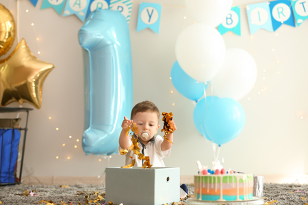 Cute little boy playing with confetti on his first birthday at homeの写真素材