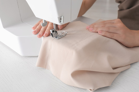 Female tailor working on sewing machine in atelier