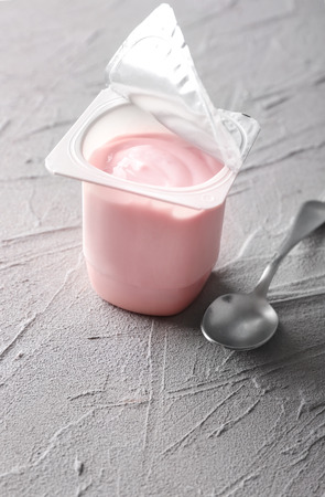 Plastic cup with yummy strawberry yogurt on grey textured backgroundの写真素材