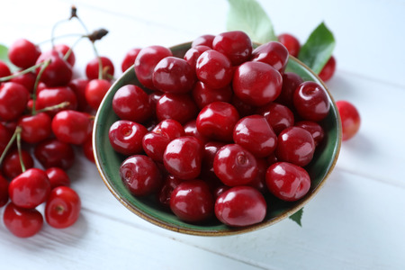 Bowl with tasty ripe cherries on wooden backgroundの写真素材