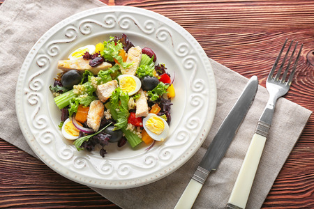 Plate with tasty chicken salad on wooden tableの写真素材