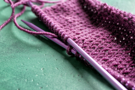 Needles with unfinished knitted clothes on color textured backgroundの写真素材