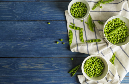 Bowls with green peas on wooden tableの写真素材