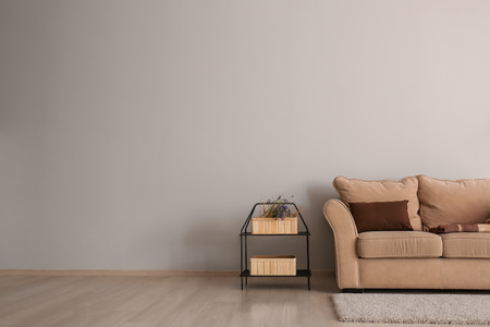 Living room with sofa and table near light wall