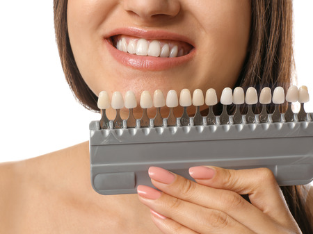Beautiful young woman with teeth color samples on white backgroundの写真素材