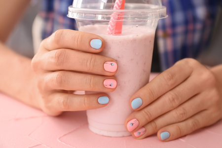 Woman with stylish color nails holding plastic glass, closeupの写真素材