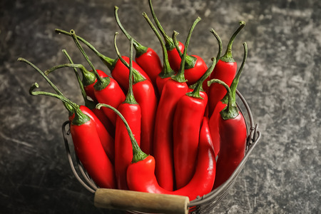 Basket with fresh chili peppers on grey background
